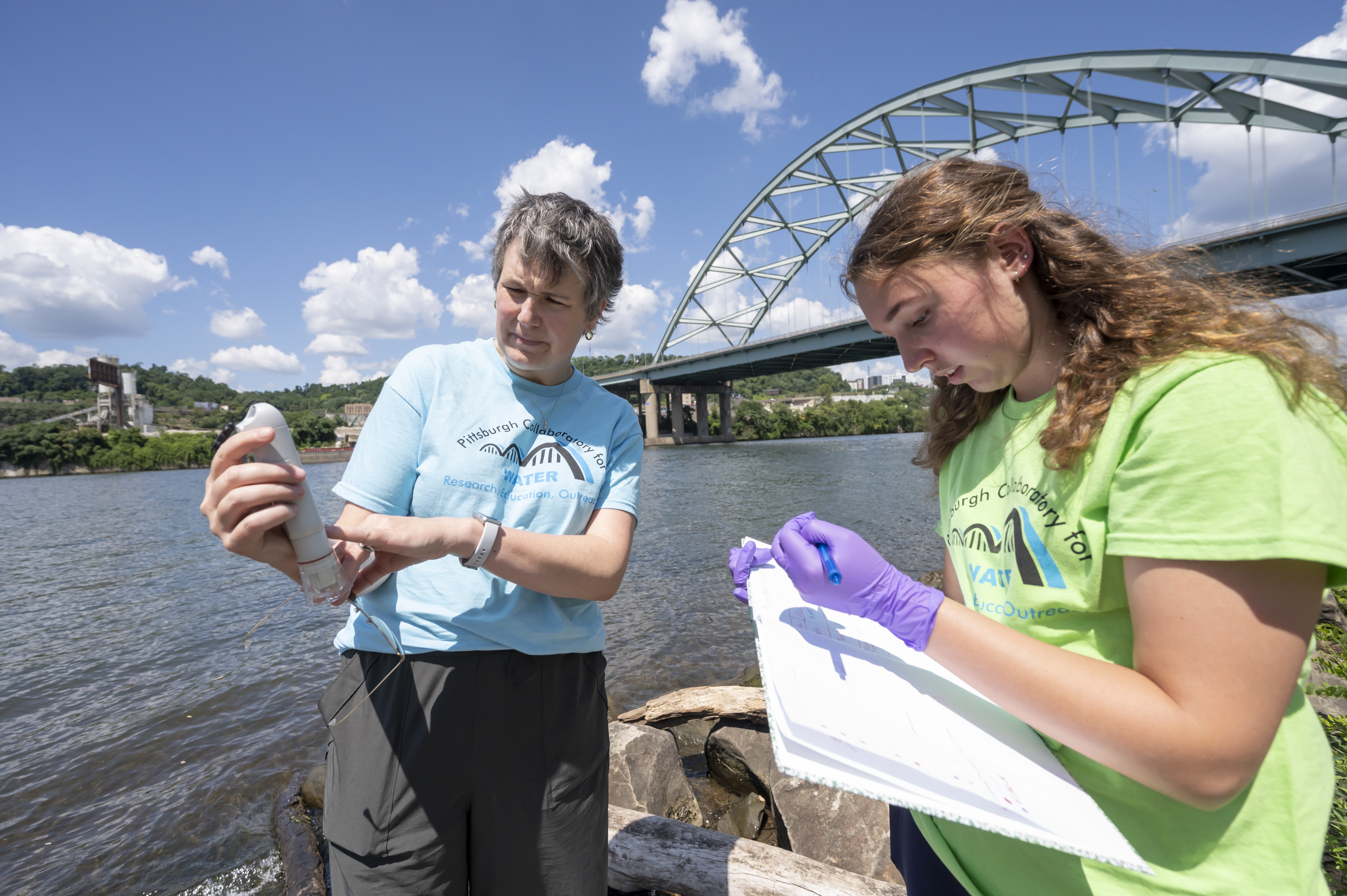 Image of women in front of river and bridge