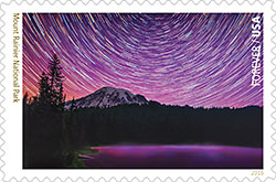 A mail stamp picturing a long exposure picture of stars swirling Mt. Rainer.