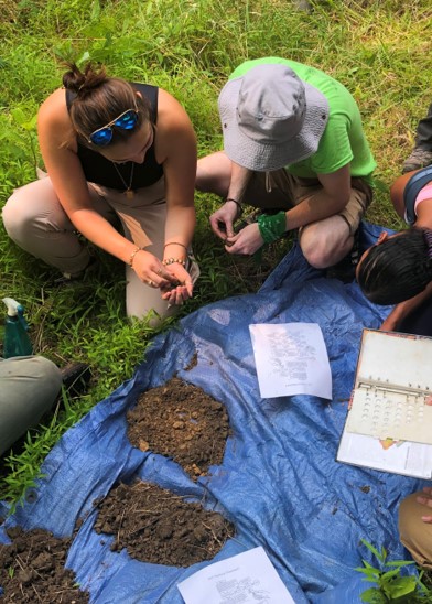 Student group inspecting findings on a tarp