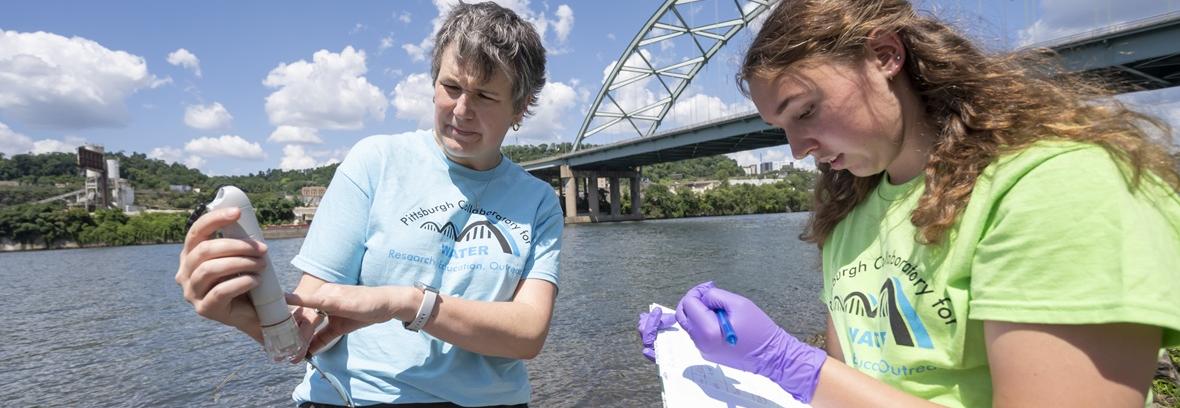 Environmenta; Science: Professor and student take notes near a river.