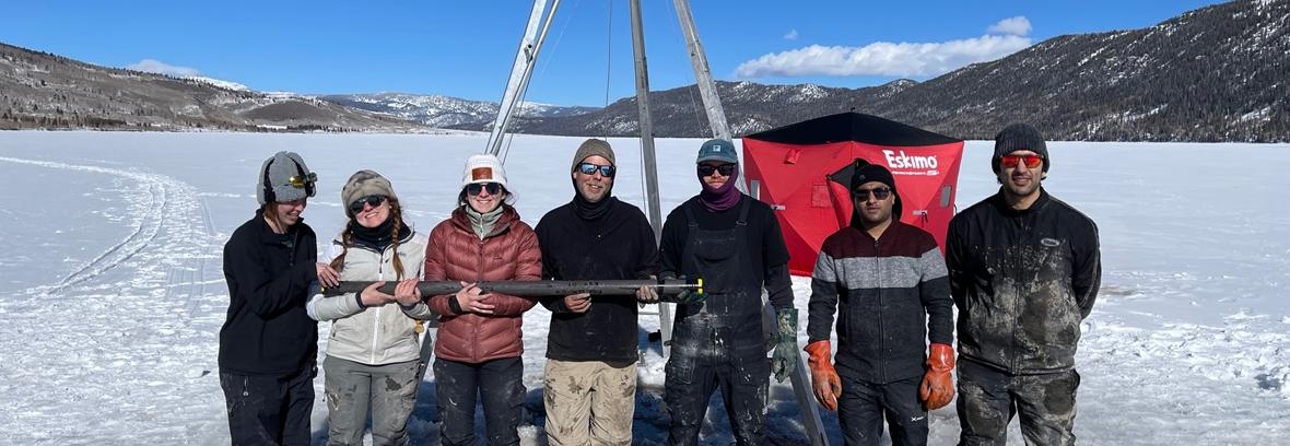 Seven people standing on a lake that is iced over.
