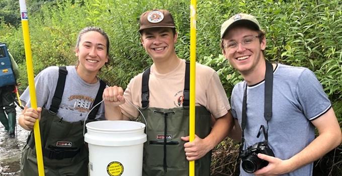 Students wearing waders standing in a creek