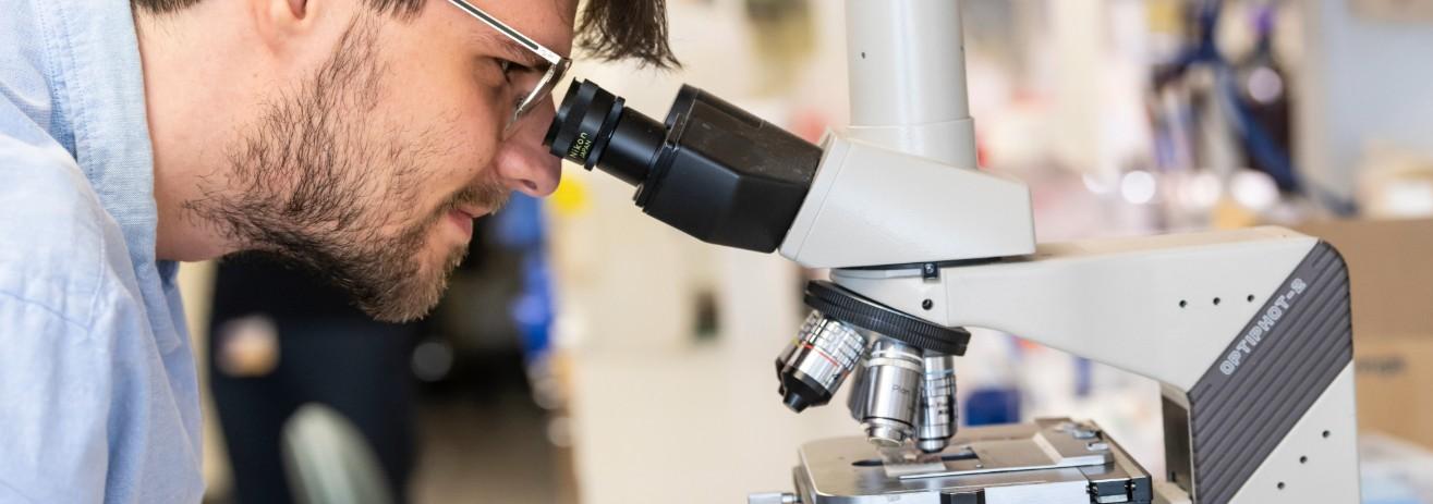 Man looking through microscope.